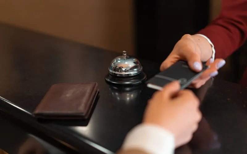 Client à la réception d'un hôtel, smartphone en main