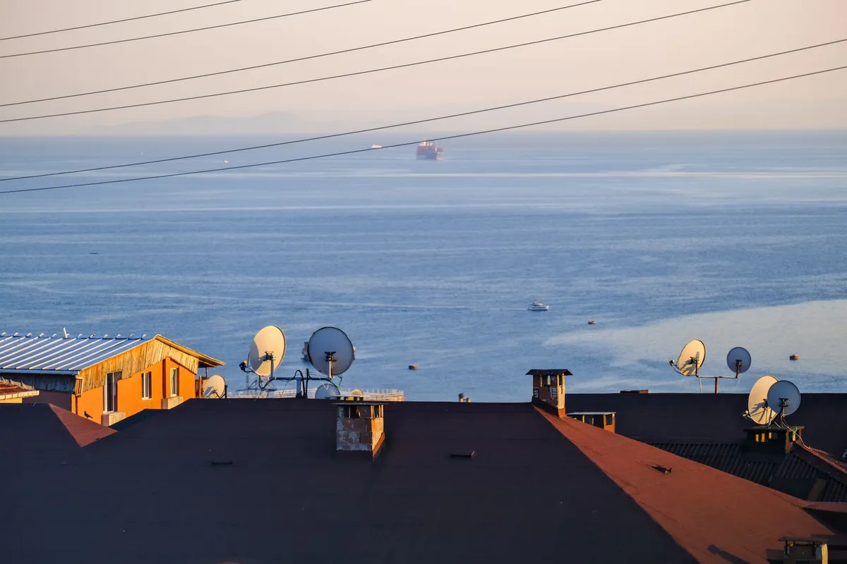 Antennes satellite sur un toit, face à la mer