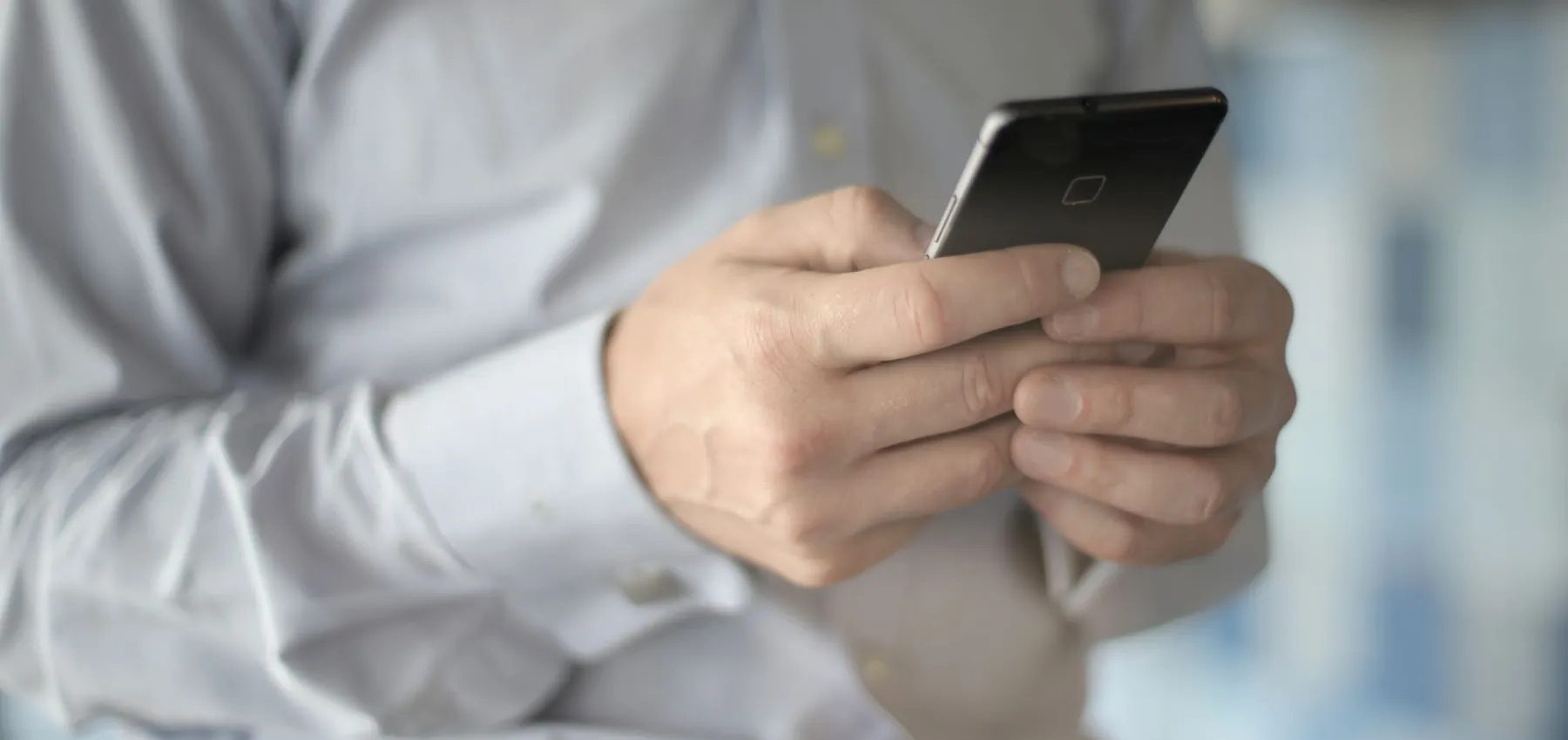 Mains d'un professionnel utilisant un smartphone au bureau